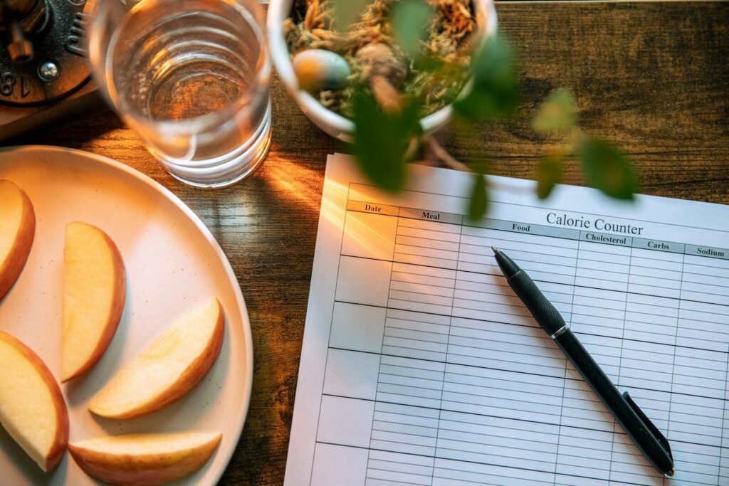 Apple slices, water glass, and a pen on a calorie counter sheet - a healthy lifestyle concept.